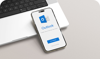Microsoft Outlook Anwendung auf dem Smartphone, das an einem Laptop angelehnt ist.