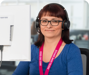 Freundliche Digital Home Service-Expertin mit Headset sitzt an ihrem Schreibtisch vor einem Computer